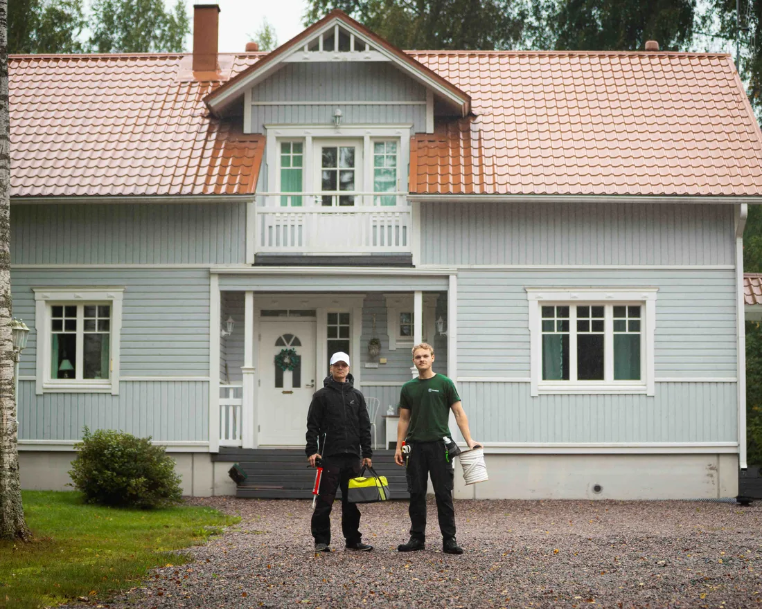 TiivisKodin asentajat vaalean puutalon pihassa työvälineineen