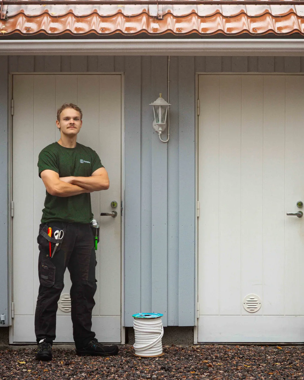Josua TiivisKodilta kahden ulko-oven edessä, tiivistekela jalkojen juuressa